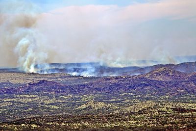 Smoke emitting from volcanic landscape against sky