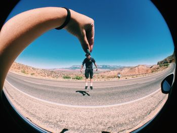 Full length of man skateboarding on road against clear sky