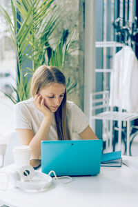 Young woman using laptop while sitting on table