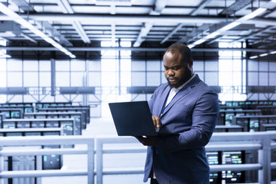 Portrait of businessman using laptop at airport