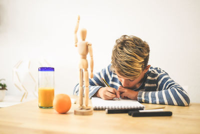 Boy drawing while sitting at table