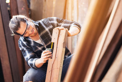 Carpenter work in wood workshop selecting timber for his woddwork