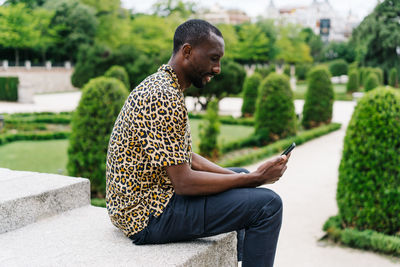 Positive afro american stylish man in european city with electronic device