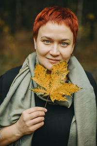 A middle-aged woman of 30-40 years old with an autumn maple leaf in her hand