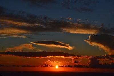 Scenic view of dramatic sky over silhouette mountains during sunset