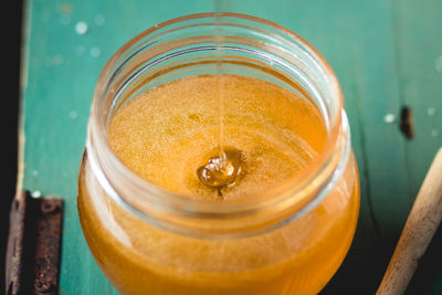 High angle view of honey falling in glass jar on table