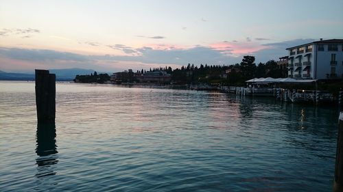 Scenic view of river by buildings against sky during sunset