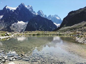 Scenic view of lake by snowcapped mountains against sky