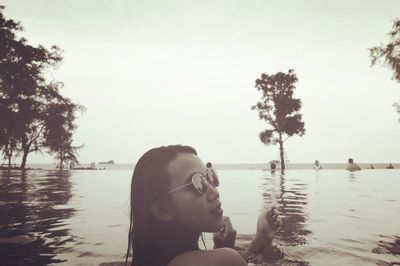 Young woman with sunglass in infinity pool against clear sky