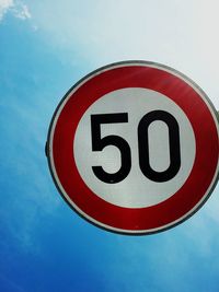 Low angle view of road sign against blue sky