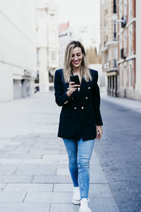 Full length of a young woman using phone in city