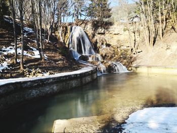 Scenic view of stream amidst trees in forest during winter