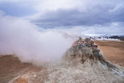 View of steaming fumarole in geothermal area of hverir at namafjall against sky