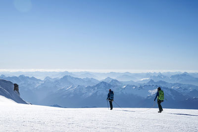 Two female mountaineers make their way across a glacier on mt. baker