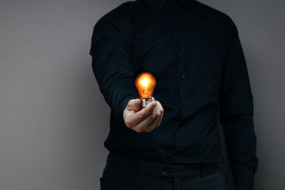 Man holding light bulb against black background