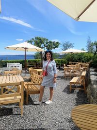 Portrait of woman standing by chair at resort