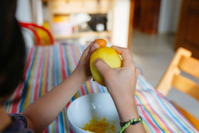 Girl with dark hair grating lemon preparing cake in the kitchen at home