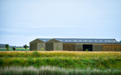 Barn or warehouse between meadows, and farmland. blue sky for text.