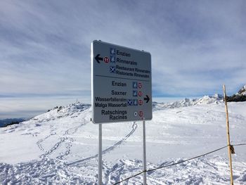 Information sign on snow field against sky