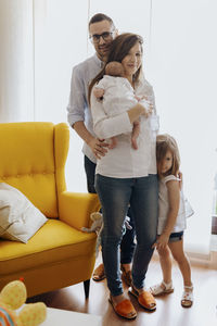 Portrait of smiling couple standing on sofa at home