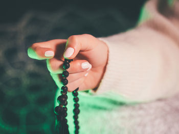 Cropped hand holding rosary beads