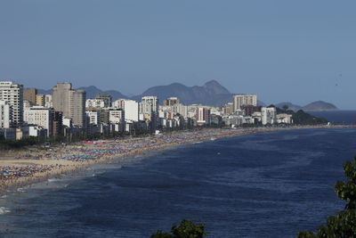 Buildings by sea against clear blue sky