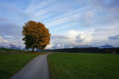 Road on green field against sky