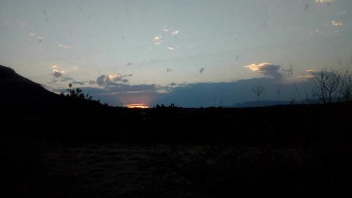 Scenic view of silhouette field against sky at sunset