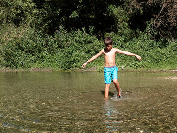 Full length of shirtless boy standing in water