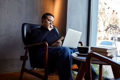 Young woman using laptop while sitting on chair at home