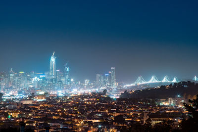 Illuminated cityscape against clear sky at night