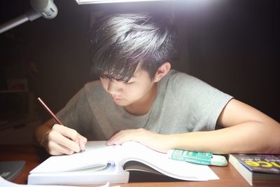 Close-up of boy studying on table at home