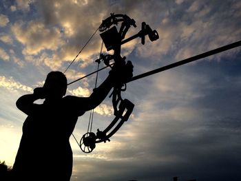 Low angle view of silhouette person practicing archery against sky during sunset