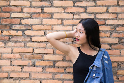 Portrait of woman standing against brick wall