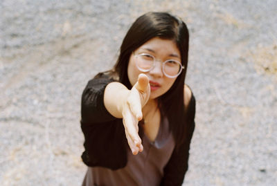 High angle portrait of young woman gesturing handshake while standing on road