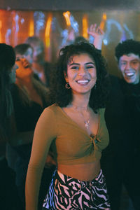 Portrait of happy woman with friend dancing in nightclub