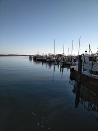 Sailboats moored in sea against clear sky