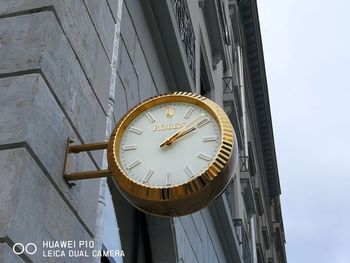 Low angle view of clock on wall against building