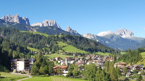 Town in valley at moena against clear blue sky