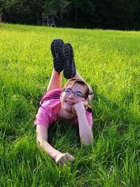 Full length of thoughtful teenage girl lying on grassy field