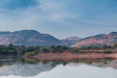 Scenic view of lake by mountains against sky