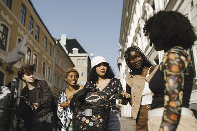 Multiracial lgbtqia friends with bicycles in city on sunny day