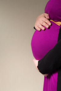 Midsection of woman holding pink flower against white background