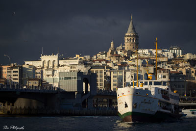 Buildings at waterfront against cloudy sky