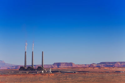 Factory on field against clear blue sky