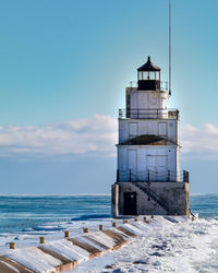 Lighthouse by sea against sky