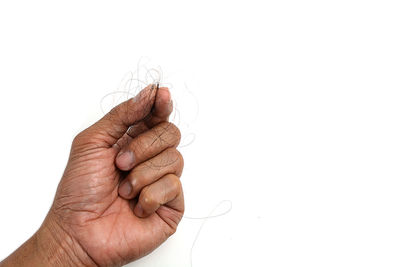 Close-up of hand holding leaf over white background
