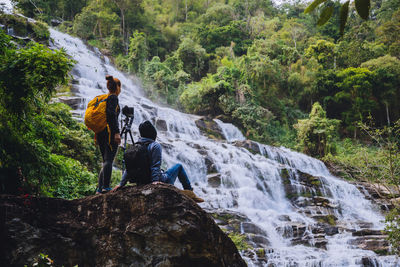 Friends photographing waterfall in forest