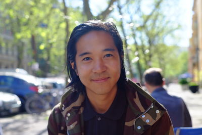 Portrait of smiling mid adult man standing against trees