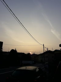 Cars on street against sky at sunset